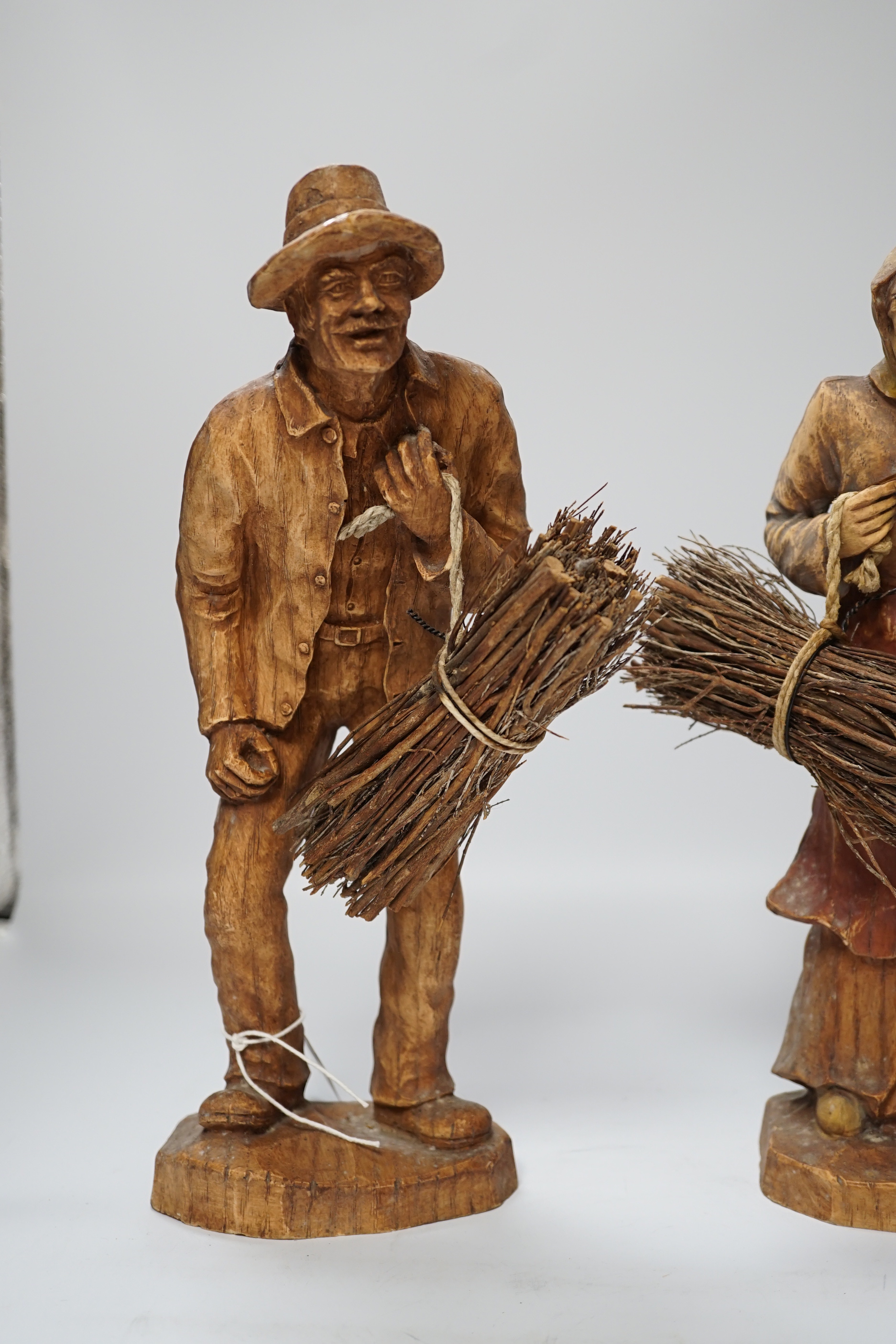 A pair of composition peasant figures gathering firewood, tallest 33cm